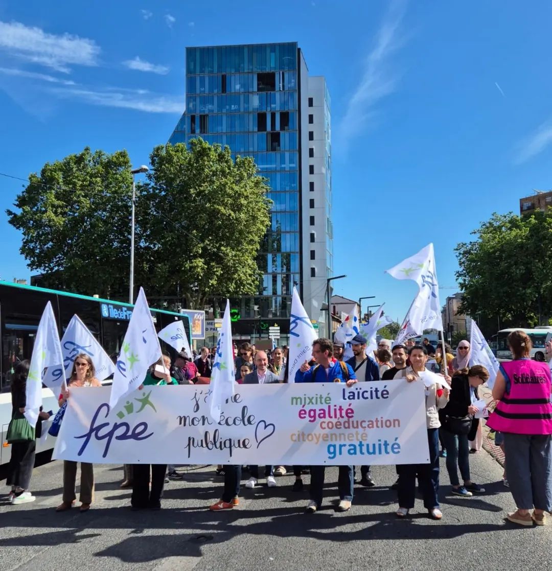 Cortège de parents, d'enseignant·es et d'enfants derrière une banderole pour l'école publique dans une rue d'Aubervilliers.